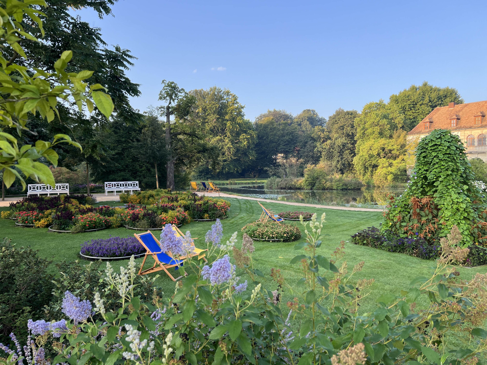 Der Schlossgarten mit Blumenbeeten und Liegestühlen.