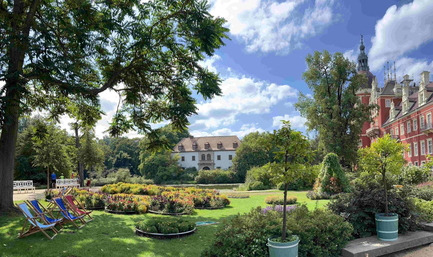 Der Schlossgarten mit Blumenbeeten und Liegestühlen, im Hintergrund das Alte und Neue Schloss.